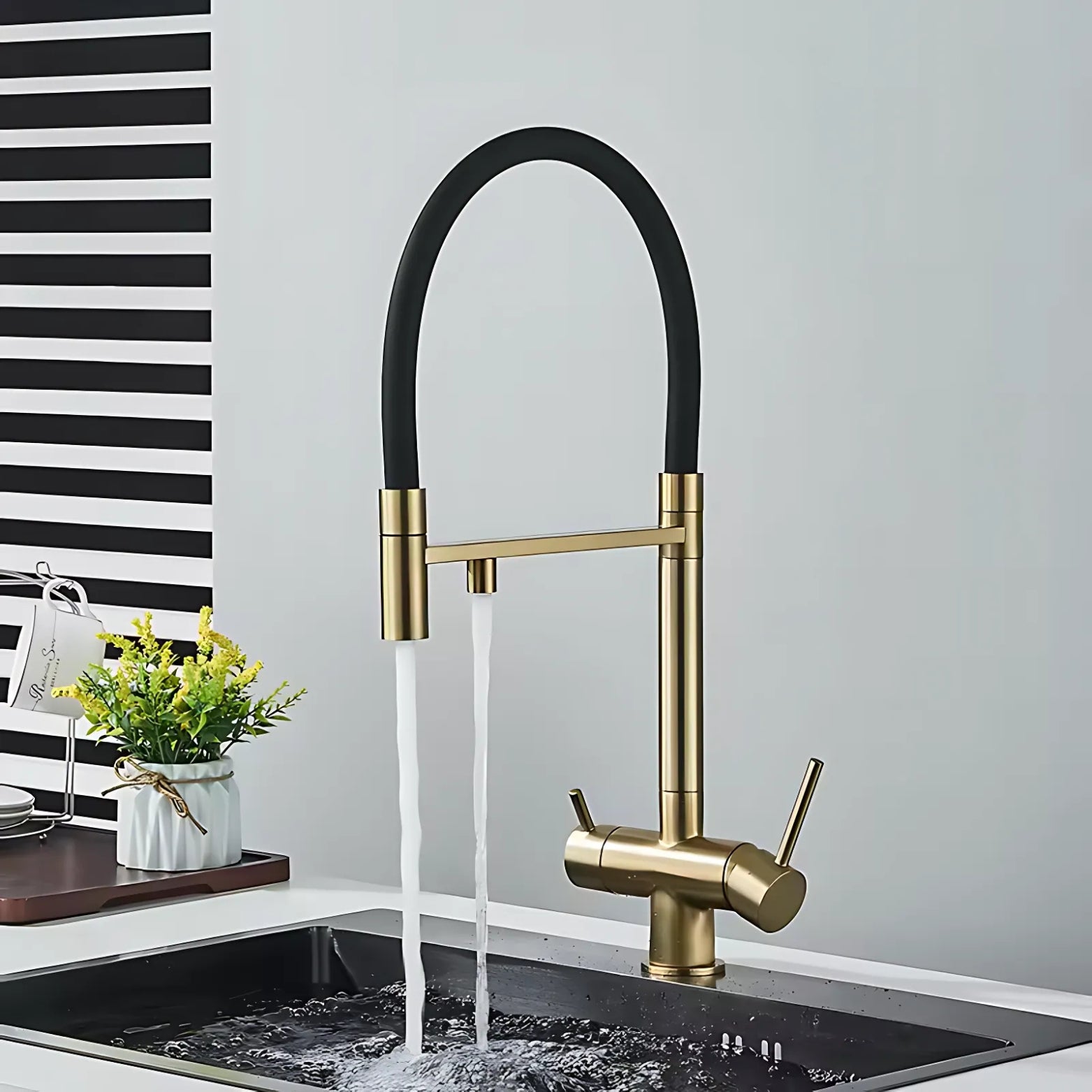 Gold and black kitchen faucet with water flowing into a sink against a neutral background