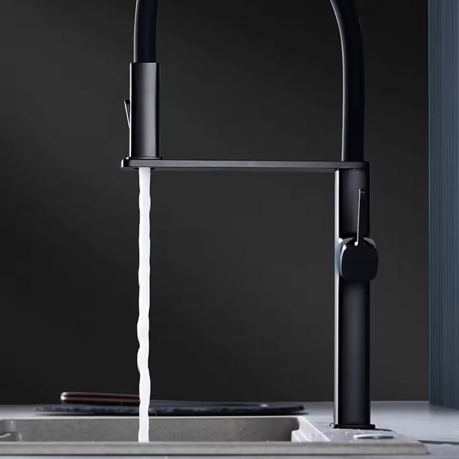 Black premium kitchen faucet with water flowing into a sink against a dark background
