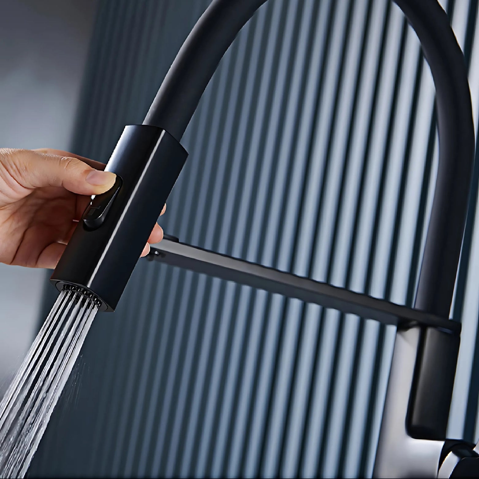 Hand holding a black premium faucet with water flowing against a gray background