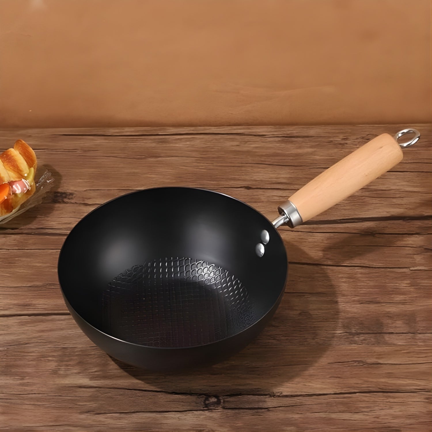 Black wok with a wooden handle on a wooden surface
