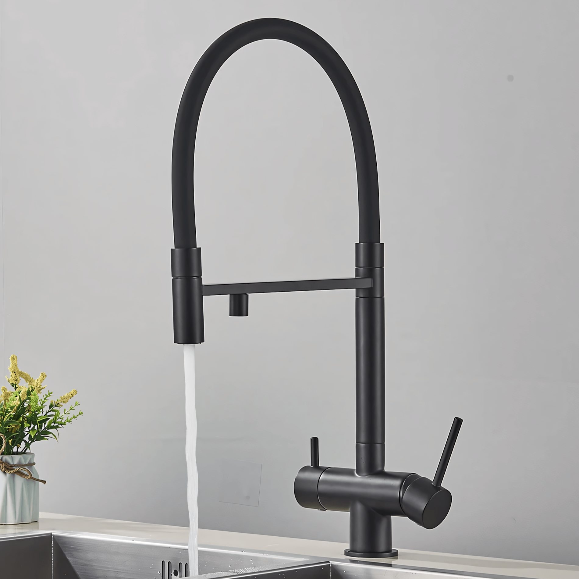 Black kitchen faucet with water flowing into a sink against a gray background